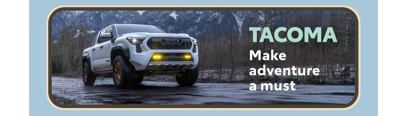 Tacoma. Make adventure a must. A white Tacoma cruises down a rainy road at dusk. Snowcapped mountains loom in the background. Explore Tacoma.